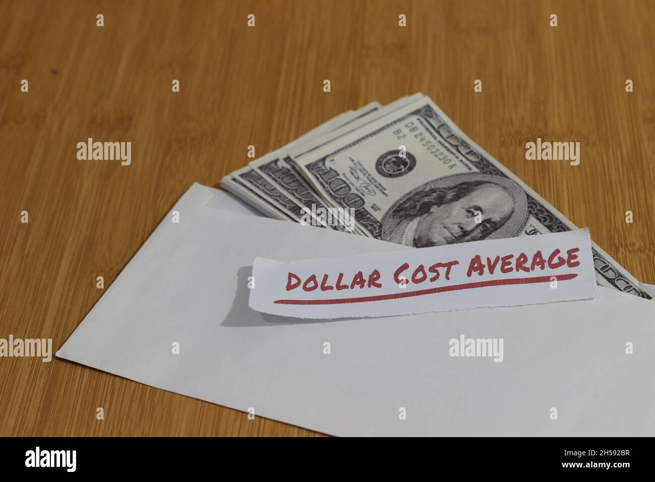Foto concettuale, carta di denaro all'interno della busta bianca e del testo costo medio del dollaro, o investimento della regola dorata di DCA Foto Stock