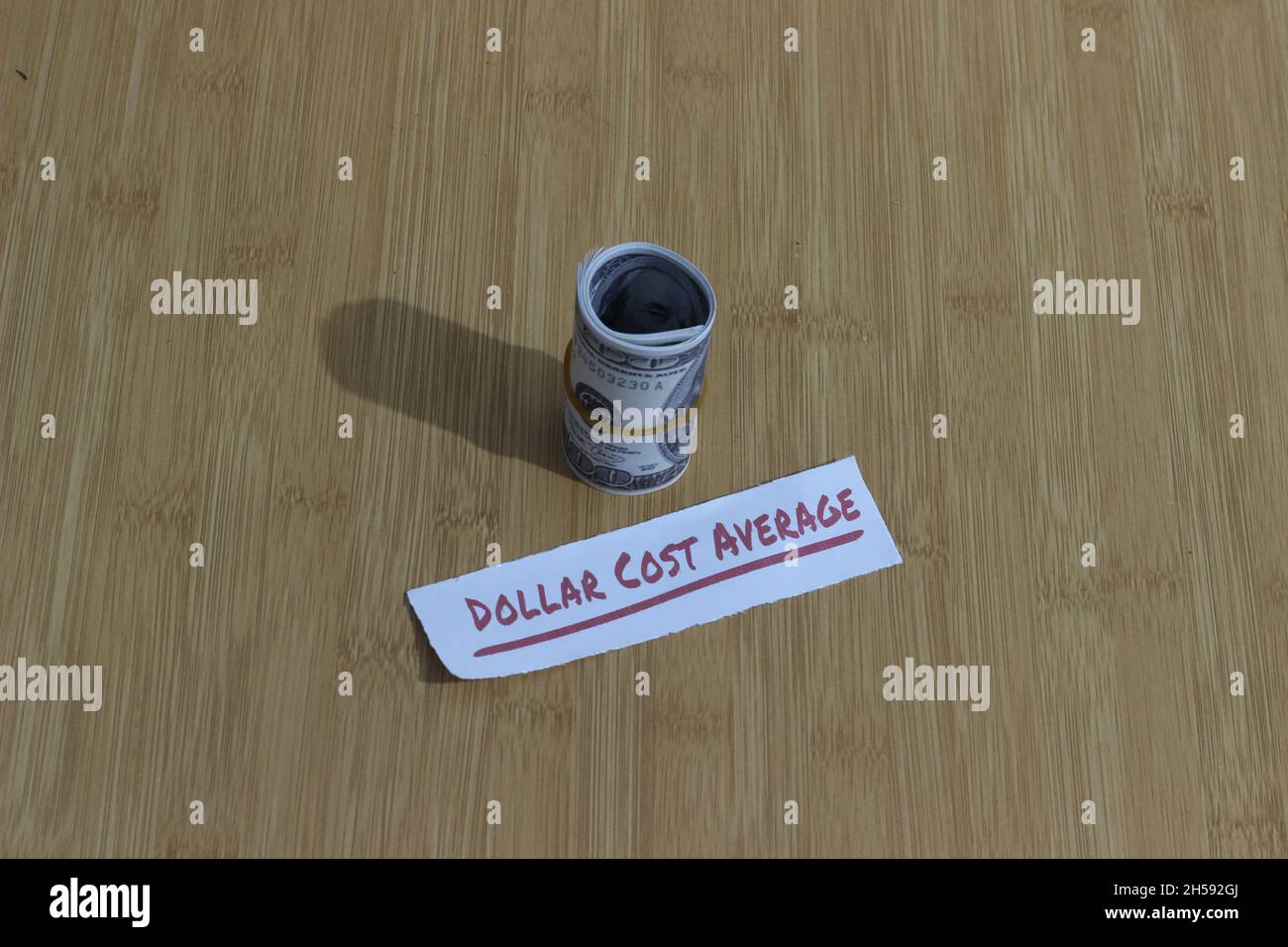 Foto concettuale, carta dei soldi stretta dalla banda della gomma e dal dollaro di testo costo medio, o investimento di regola d'oro di DCA Foto Stock