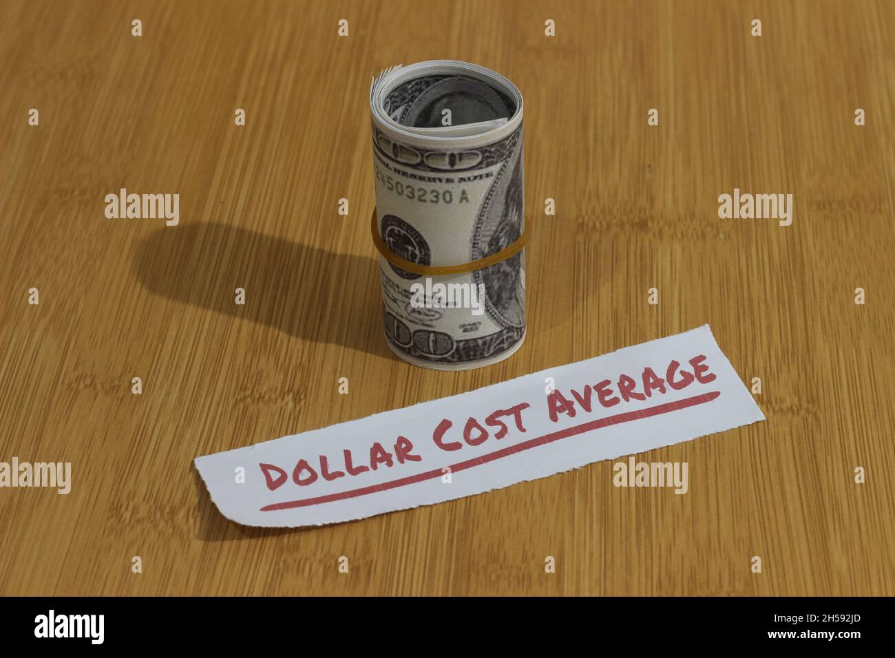 Foto concettuale, carta dei soldi stretta dalla banda della gomma e dal dollaro di testo costo medio, o investimento di regola d'oro di DCA Foto Stock