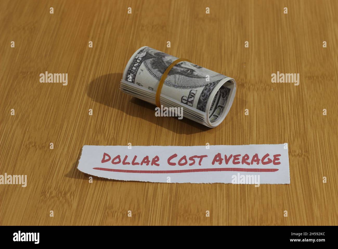 Foto concettuale, carta dei soldi stretta dalla banda della gomma e dal dollaro di testo costo medio, o investimento di regola d'oro di DCA Foto Stock