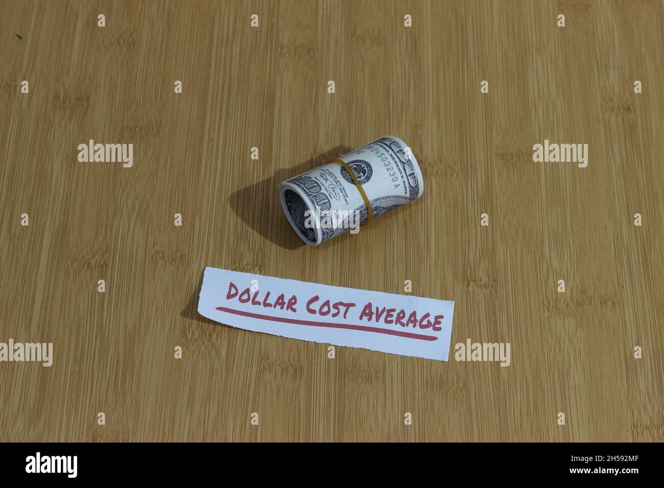 Foto concettuale, carta dei soldi stretta dalla banda della gomma e dal dollaro di testo costo medio, o investimento di regola d'oro di DCA Foto Stock