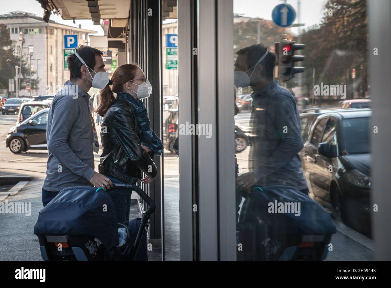 Immagine di un uomo e di una donna con un bambino in un passeggino osservando il negozio di un negozio nelle strade di Belgrado, Serbia, indossando una protezione Foto Stock