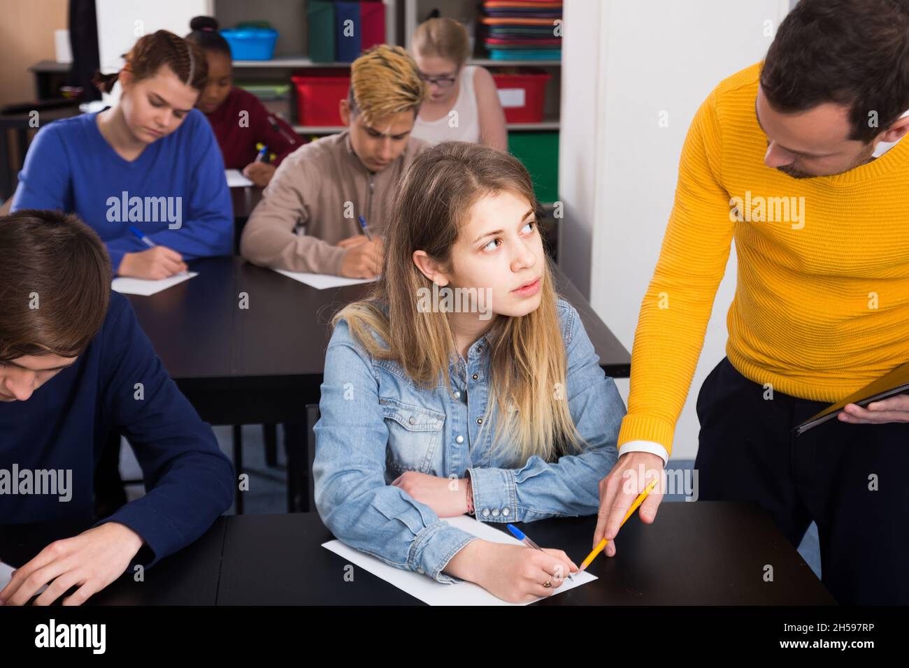 Insegnante di sesso maschile che chiariscono problemi complicati alla pupilla durante l'esame in classe Foto Stock