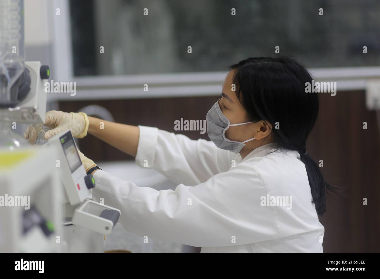 Scienziato asiatico donna che opera un evaporatore rotante per fare un esperimento in laboratorio Foto Stock