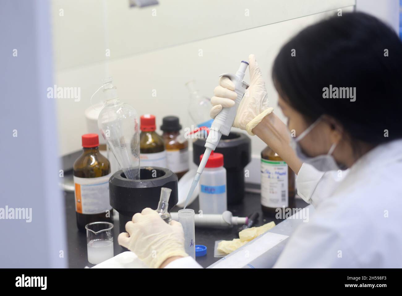 Scienziata asiatica con pipetta per fare un esperimento in laboratorio Foto Stock