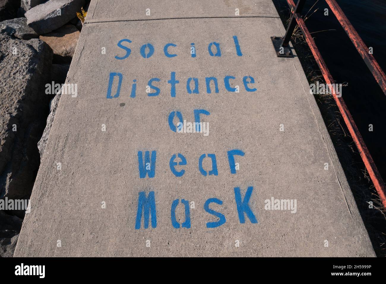 social distance o indossare maschera sul marciapiede riconette Foto Stock