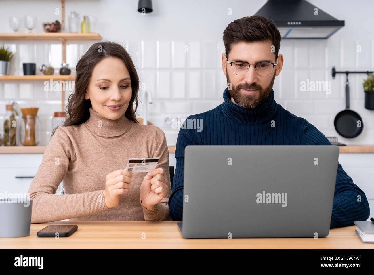 Coppia di famiglia che usa il portatile e la carta di plastica per il pagamento sicuro del Internet Foto Stock