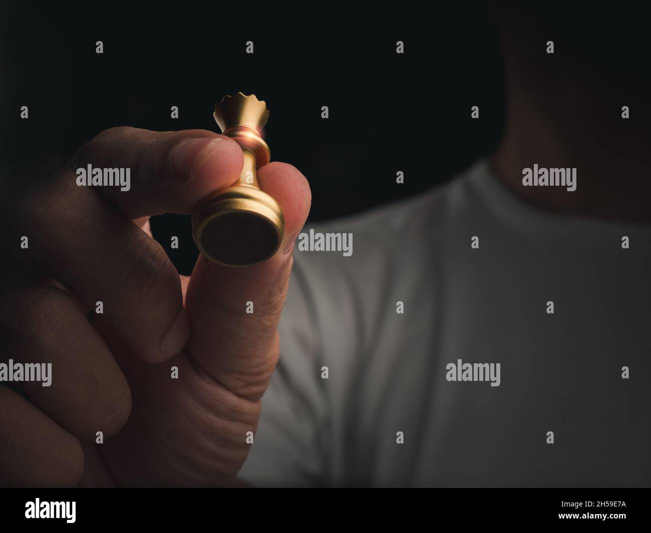 Pezzo di scacchi della regina d'oro in mano umana in aria su sfondo scuro con spazio copia. La figura di scacchi della regina in movimento a mano pronta ad attaccare il nemico sulle fosse Foto Stock