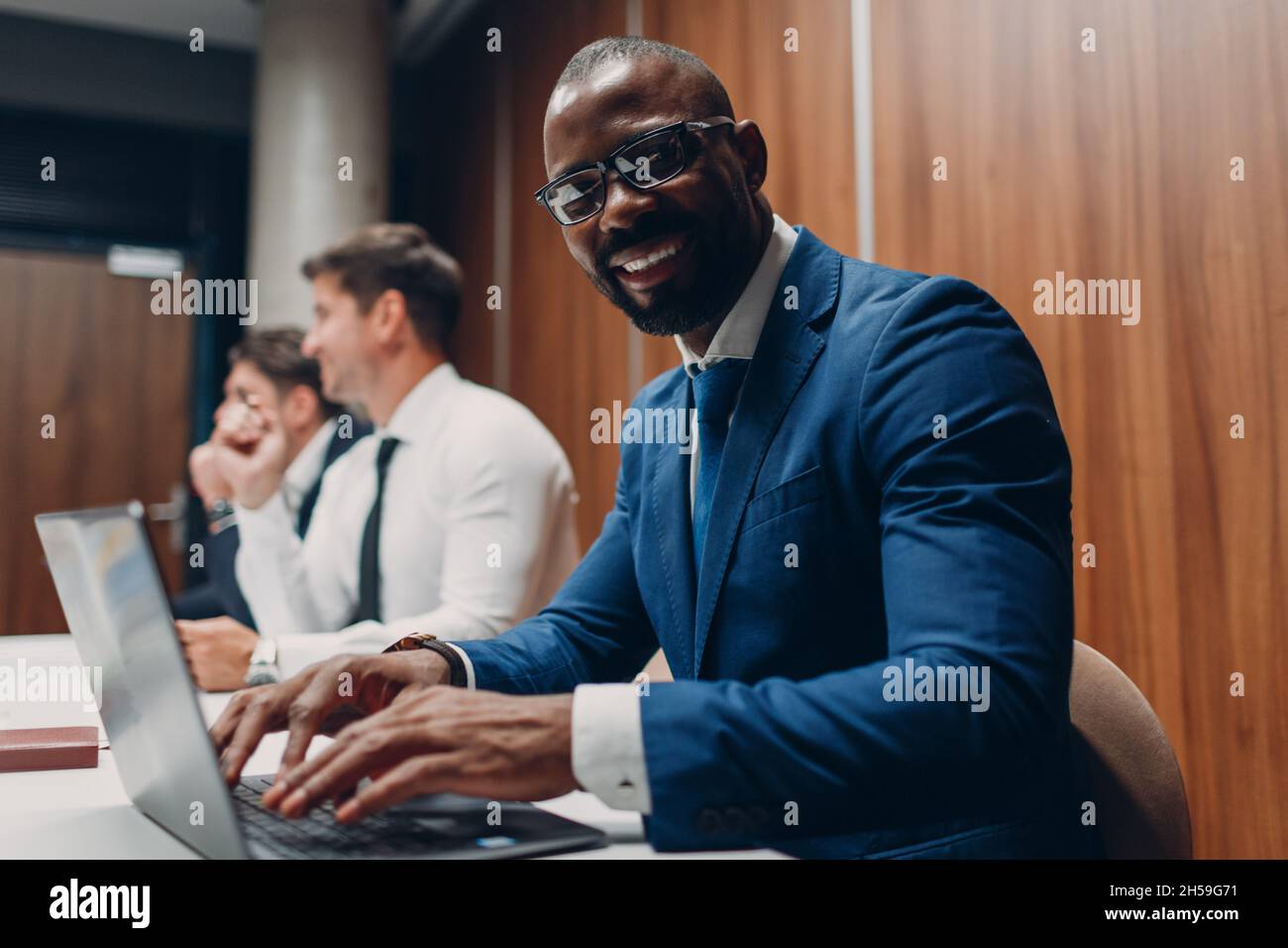 Uomo d'affari nero africano americano seduto al tavolo con il computer portatile in ufficio. Consulenza e consulenza Foto Stock