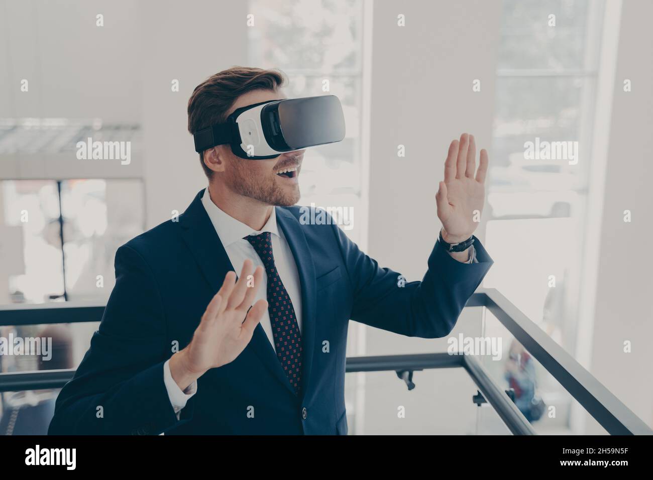 Uomo d'affari in tuta utilizzando occhiali per realtà virtuale in ufficio Foto Stock