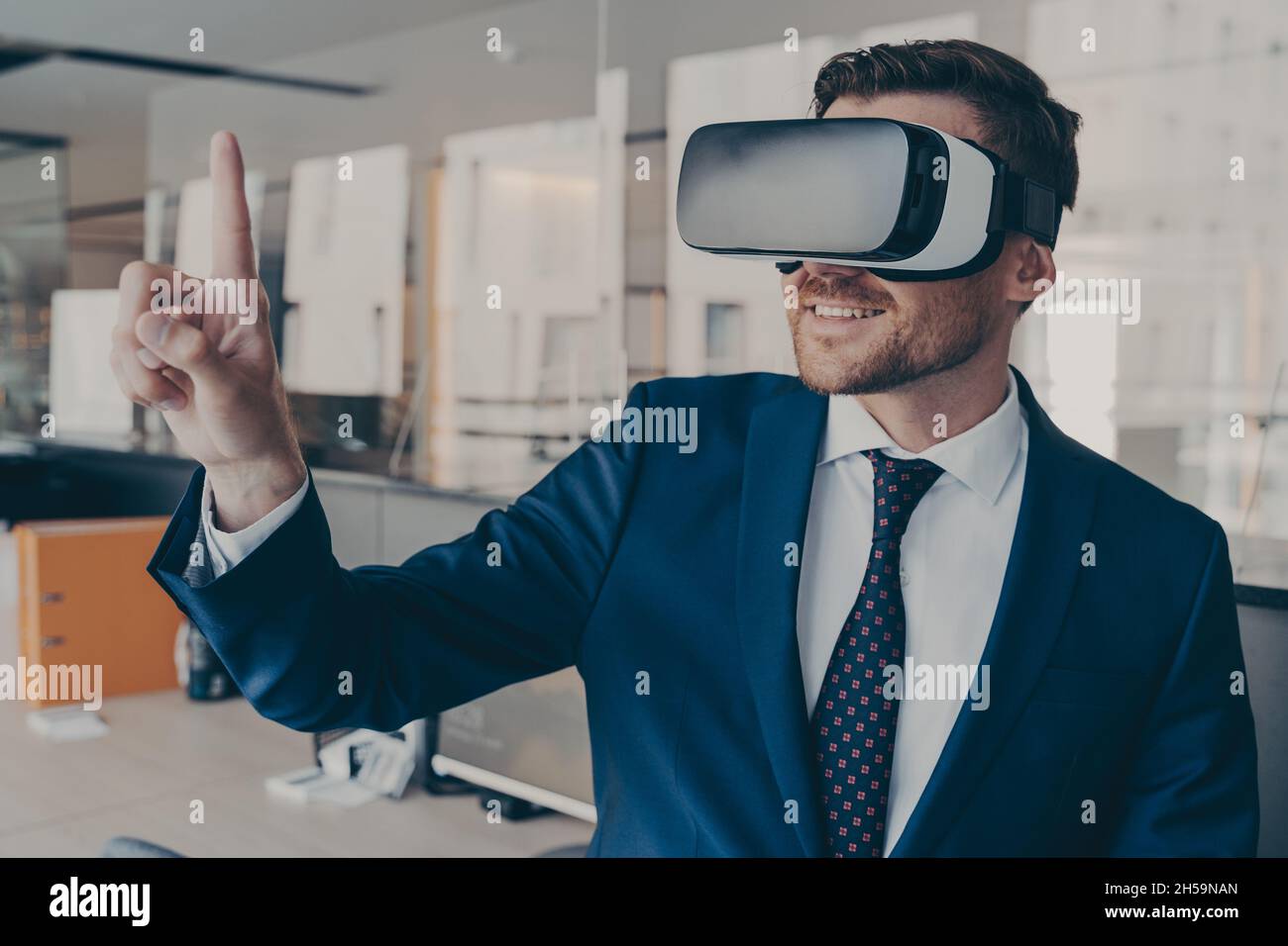 Giovane finanziatore che indossa occhiali per visore VR, mentre si trova in ufficio Foto Stock