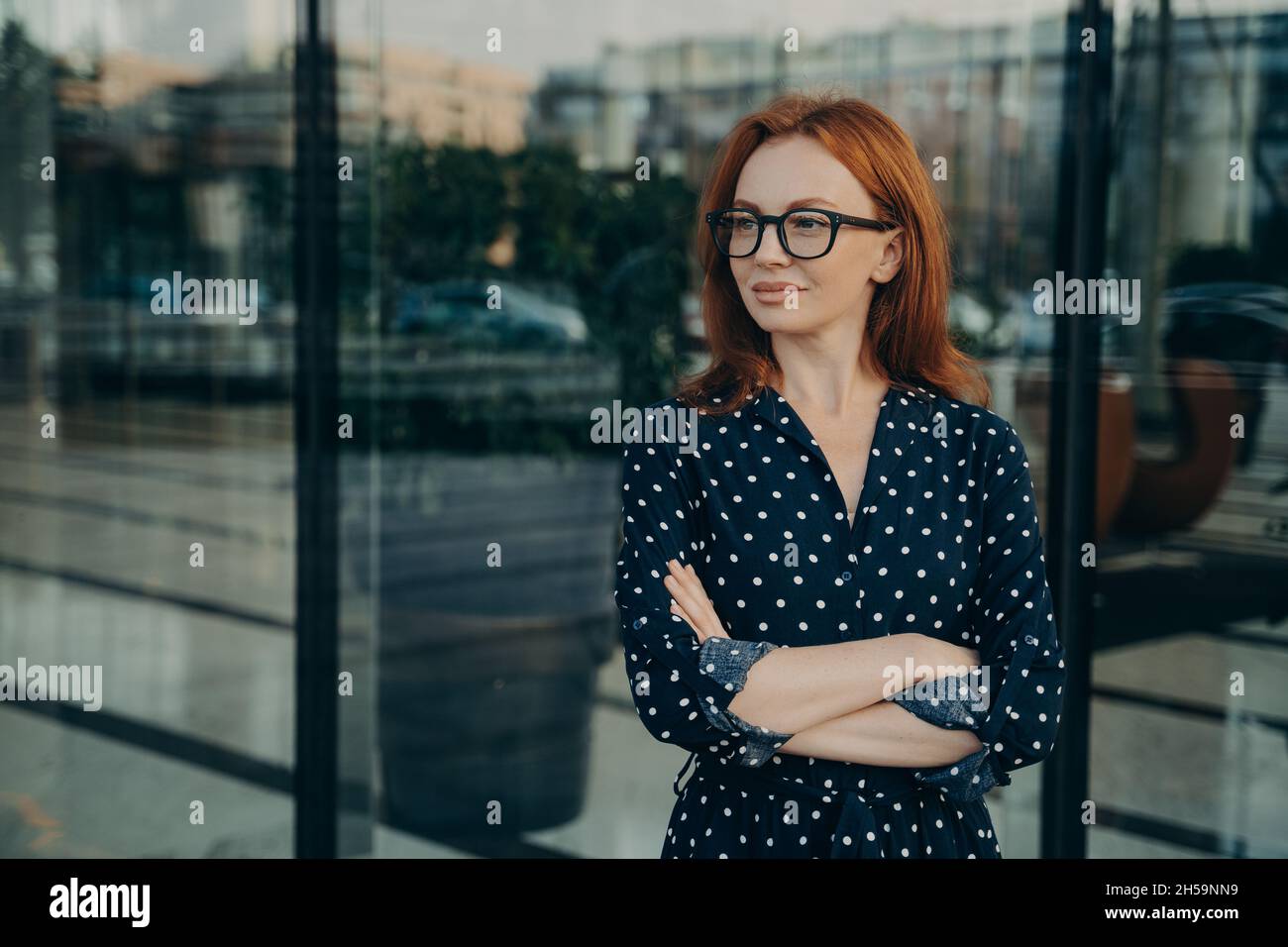 La donna europea della testa rossa pensiva guarda via mantiene le braccia piegate fa i piani in mente Foto Stock