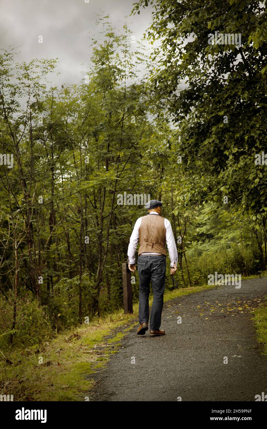 Uomo in gilet e jeans Walking in Woods Foto Stock