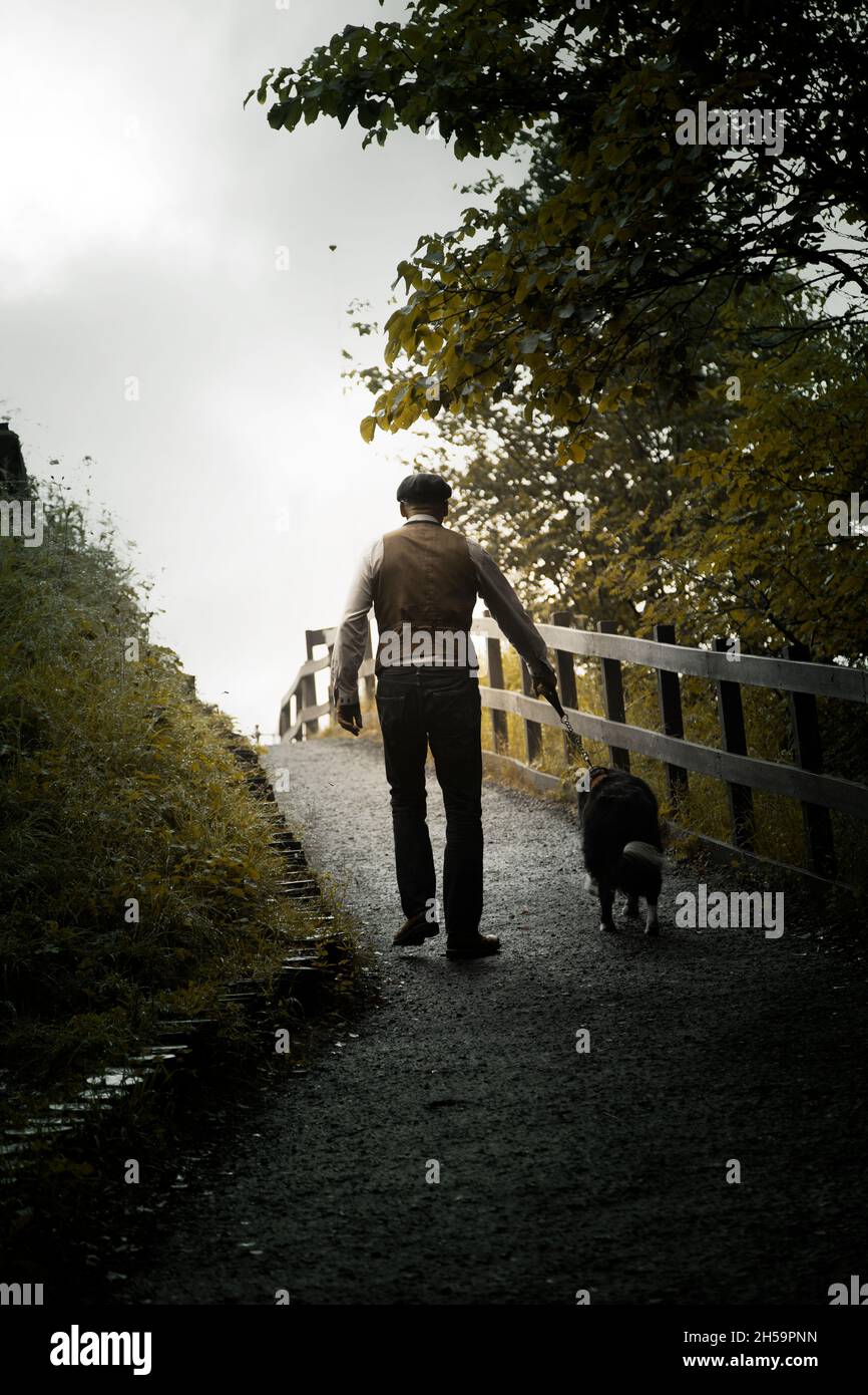 Uomo in gilet e jeans Walking in Woods con cane Foto Stock