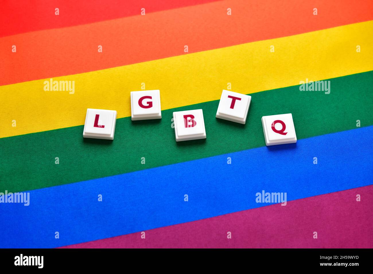 Spielbuchstaben bilden den Schriftzug LGBTQ auf Regenbogenfahne Foto Stock