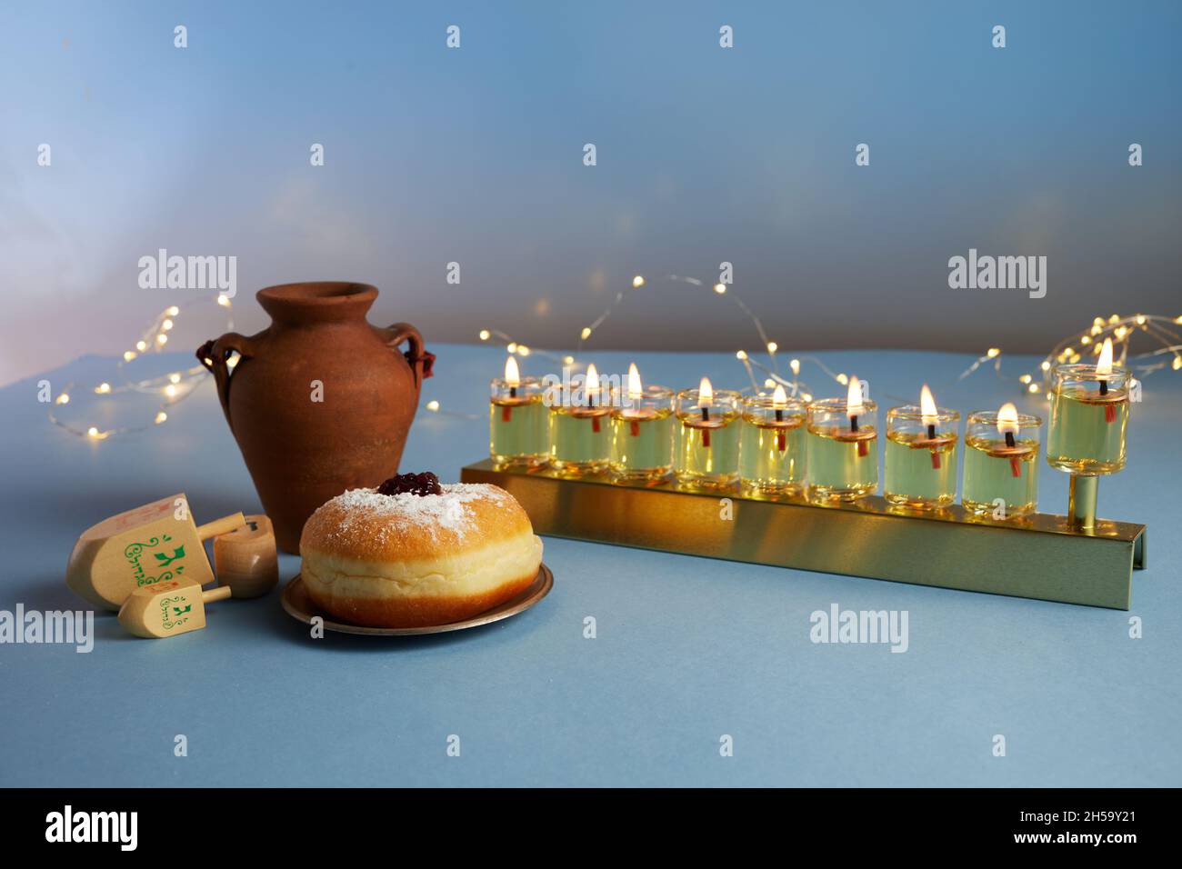 Vacanza ebraica Hanukkah sfondo con menorah tradizionale candelabra, filatura top e ciambella su sfondo blu Foto Stock