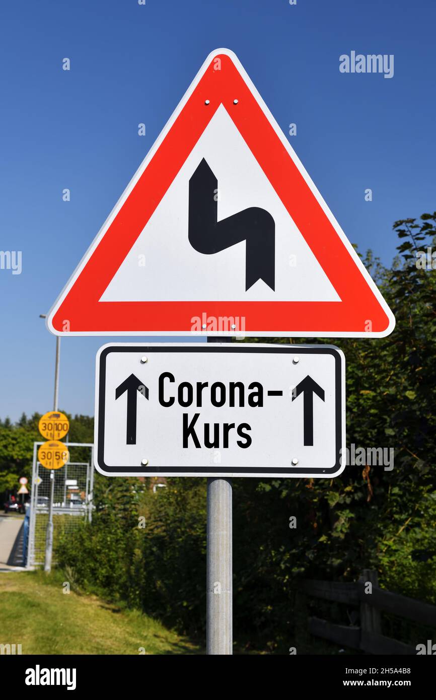 FTOMONTAGE, Schild mit Kurvensymbol und Aufschrift Corona-Kurs, Symbolfato fuer Schlingerkurs in der Corona-Pandemiebekaempfung Foto Stock