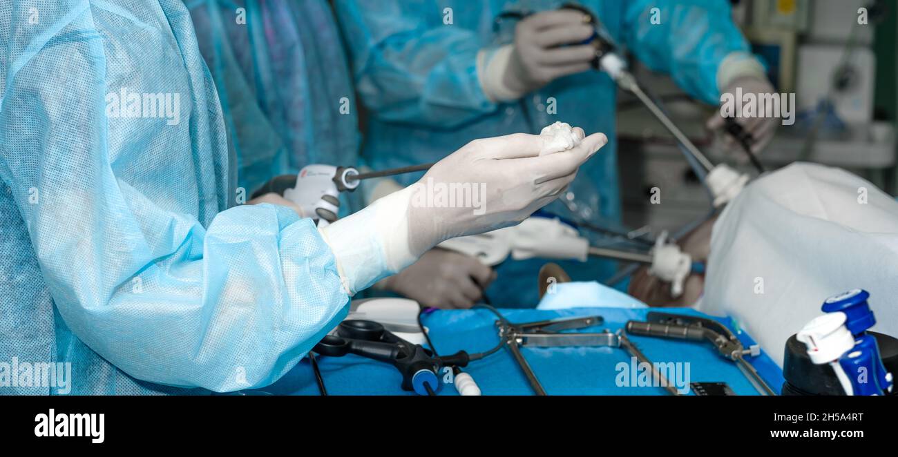 Manipolatore laparoscopico chirurgico per chirurgia proctologica minimamente invasiva nelle mani di un chirurgo. Messa a fuoco selettiva. Immagine widescreen. Foto Stock