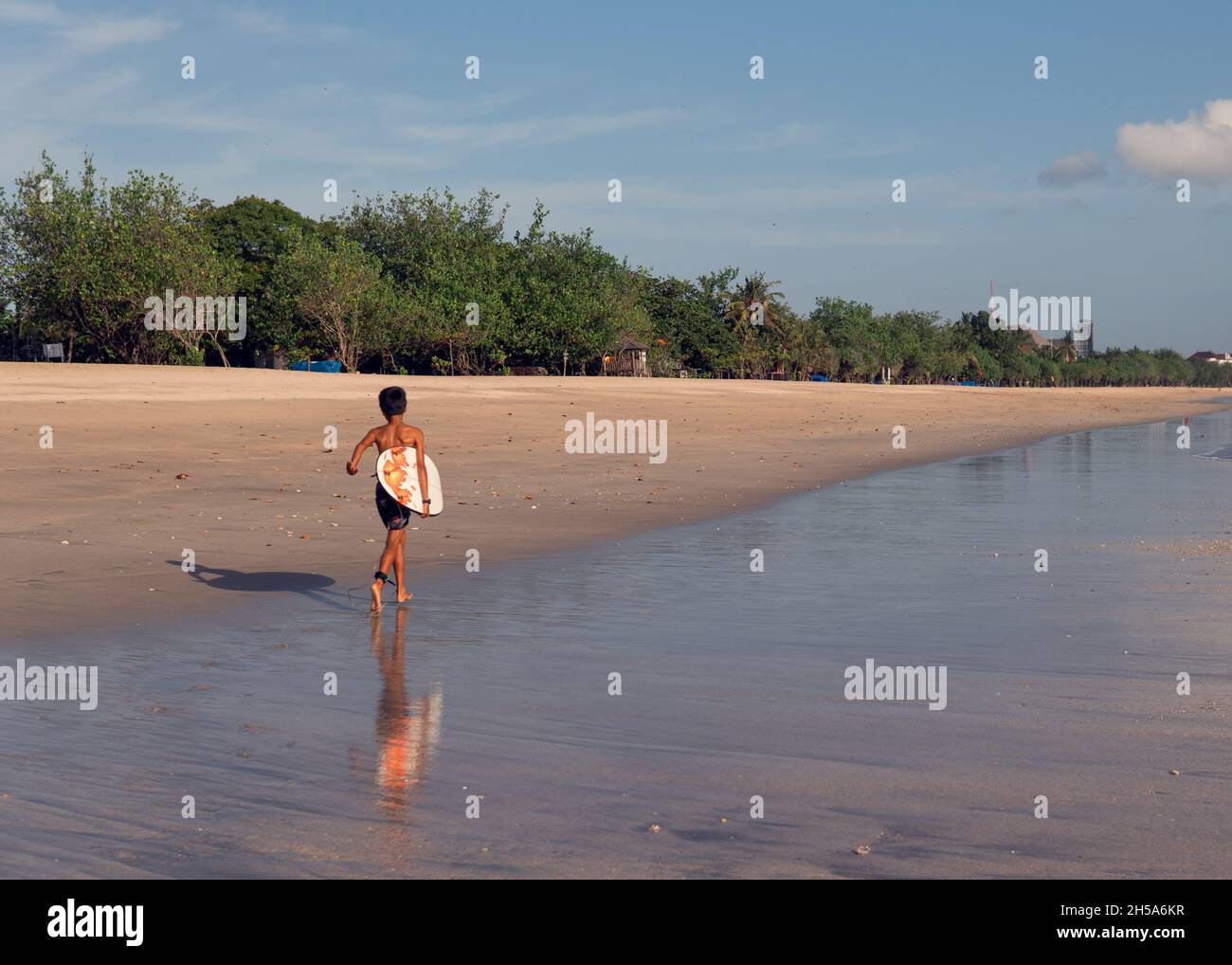 surfista con tavola bianca che cammina lungo la spiaggia. bali Foto Stock