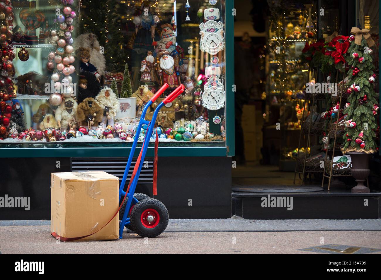 Scatola di cartone su un carrello contro la finestra del negozio di decorazione di Natale Foto Stock