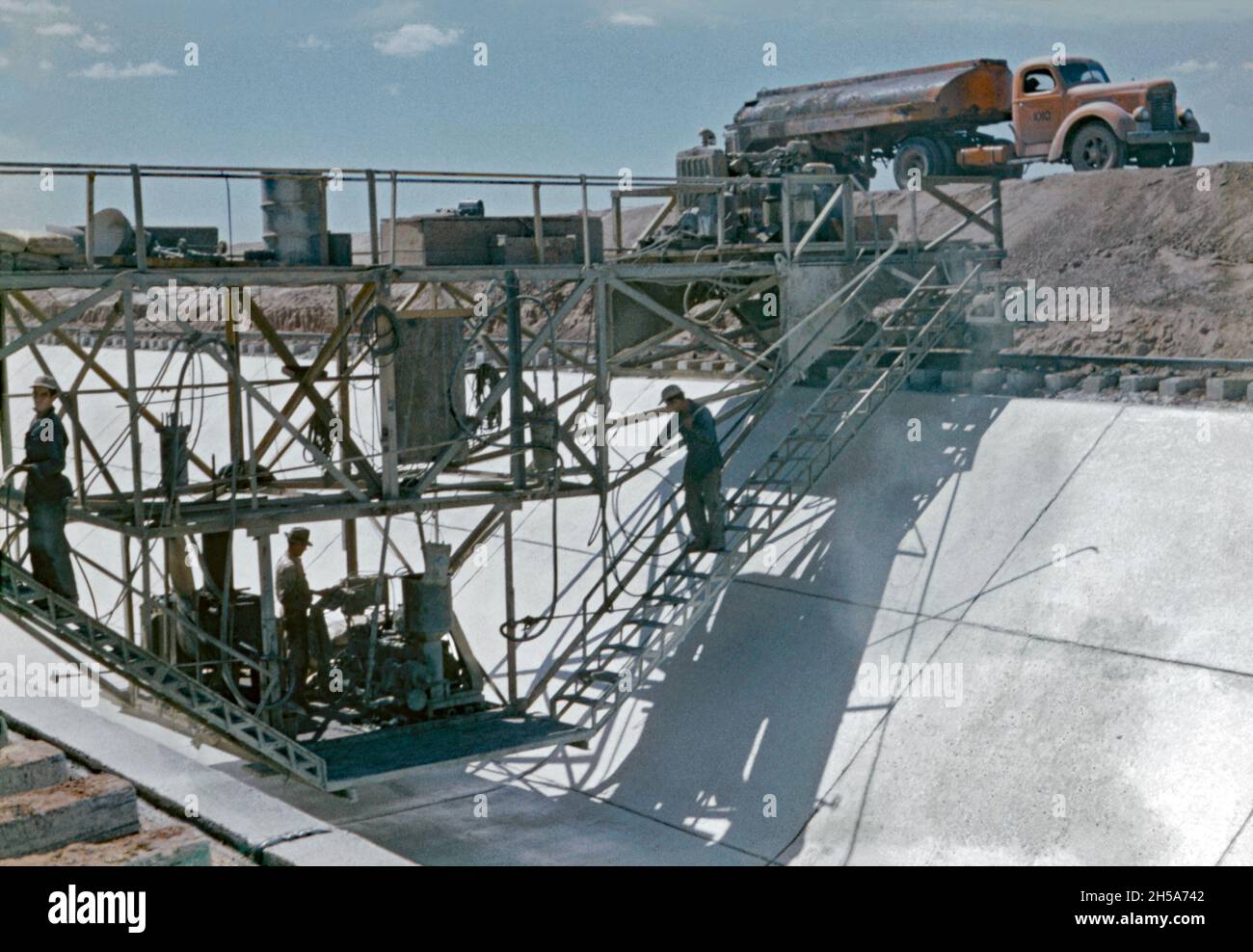 Lavori di costruzione sul canale di Wellton-Mohawk, vicino a Yuma, Arizona, USA nei primi anni '50. Qui i lavoratori di un carro su rotaie si muovono lungo il calcestruzzo appena posato. Stanno sfondando la base e i lati inclinati del canale per evitare che il materiale di rivestimento si indurisce troppo rapidamente e si rompa. Il Wellton-Mohawk Irrigation and Drenaggio District si trova nel sud-ovest dell'Arizona, ad est di Yuma, costruito tra il 1949 e il 1957. Permette l'irrigazione nella valle inferiore di Gila con acqua dal fiume Colorado attraverso il canale di Gila al canale di Wellton-Mohawk, dove è pompato circa 160 piedi alle acque headwaters Foto Stock