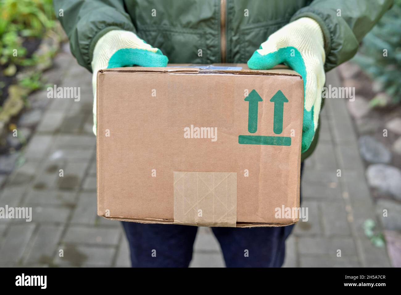 L'addetto alla consegna tiene un pacco con un simbolo fragile su una scatola di cartone. Consegna del servizio di corriere pacchi a casa vostra. Invio di articoli fragili Foto Stock