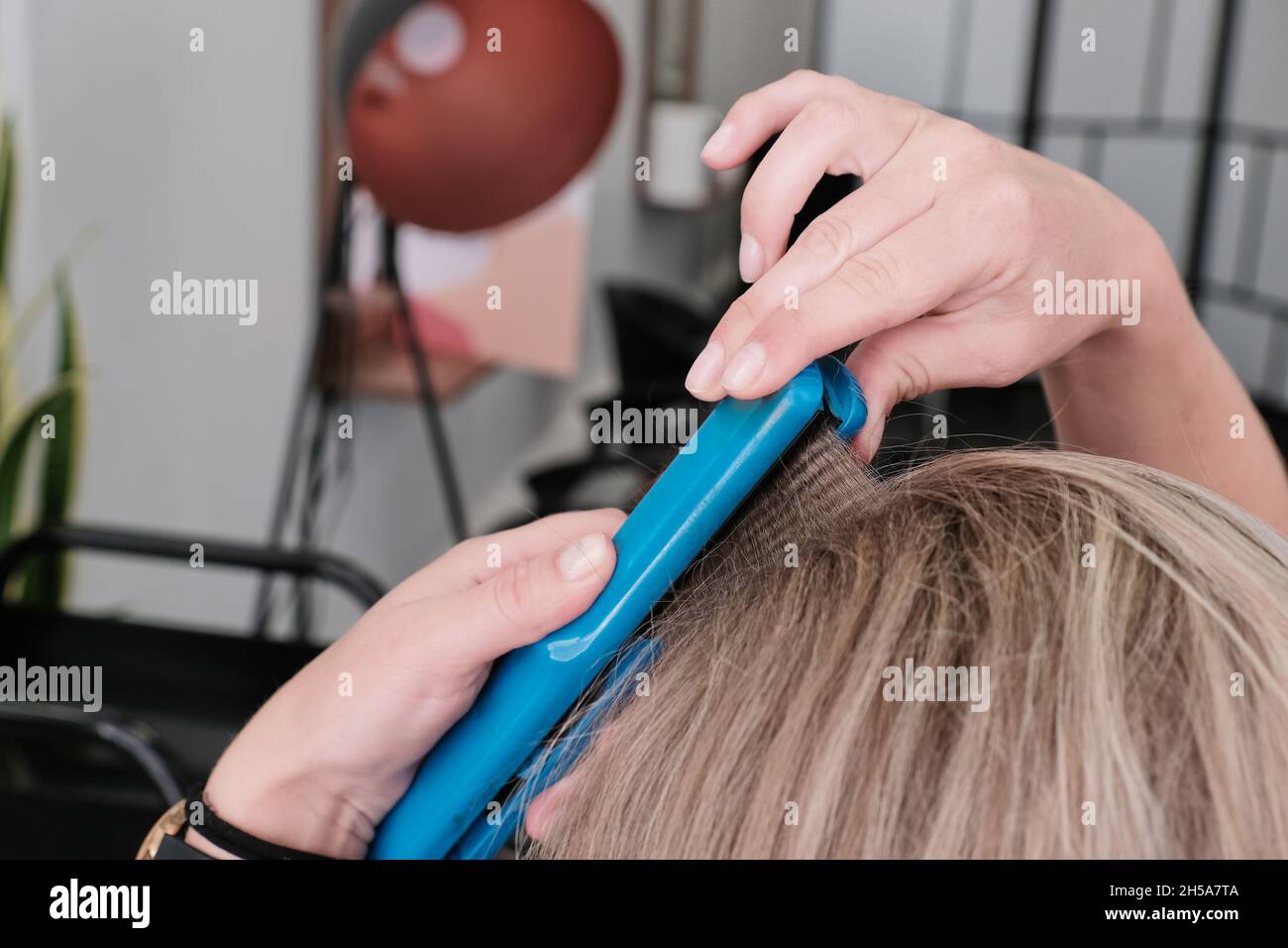 Styling dei capelli con un ferro da stiro. Piastra per capelli corrugata aggiungendo consistenza e volume ai capelli. Foto Stock