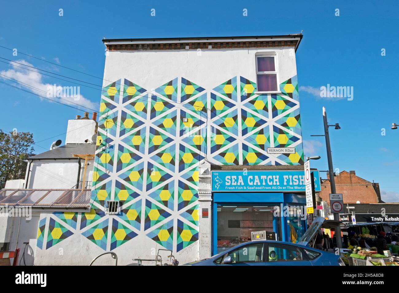 Murale colorato sul lato dell'edificio in Vernon Road e Sea Catch Fish Store all'angolo di Walthamstow High Street, sotto il sole d'autunno del 2021 ottobre Foto Stock