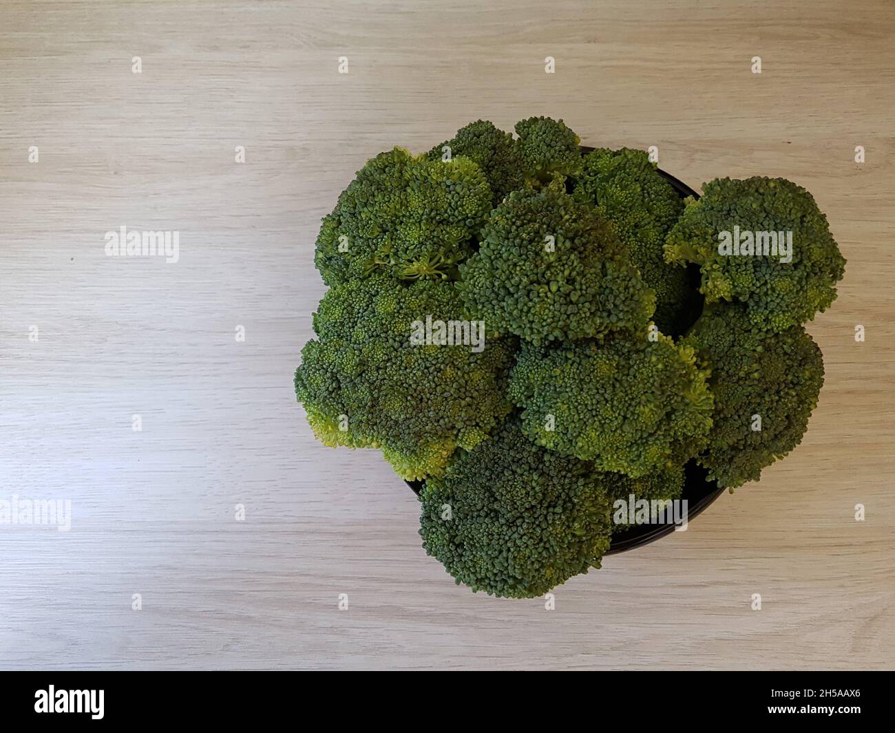Broccoli: Verdi, biologici, isolati, pronti per cucinare su un tavolo di legno chiaro. I broccoli (di origine italiana) sono una pianta della famiglia delle Brassicaceae. Foto Stock