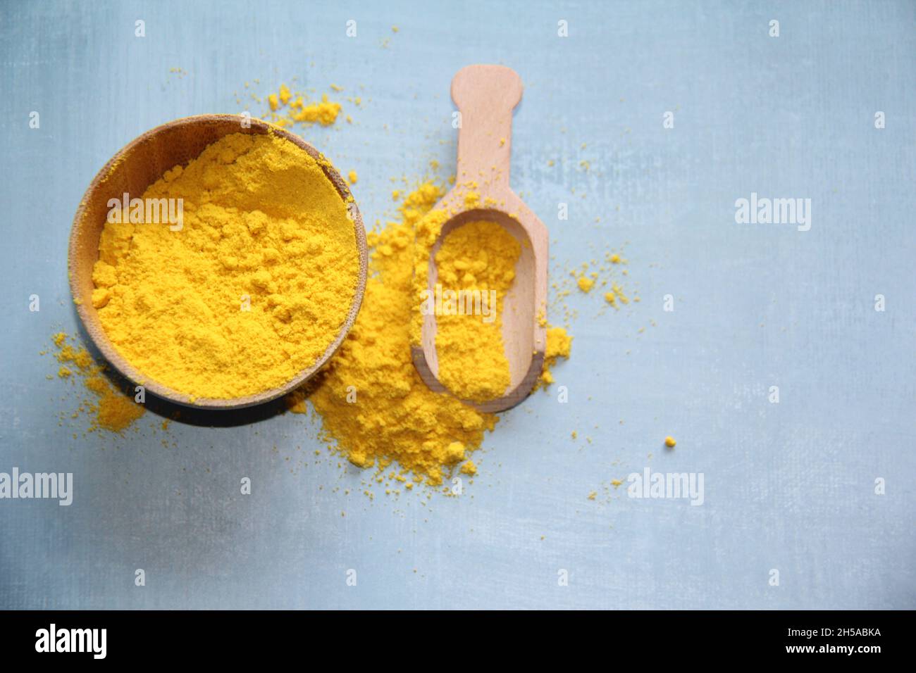 Mostarda in polvere in una ciotola di legno con un misurino di legno su un vecchio tavolo di legno. Foto Stock