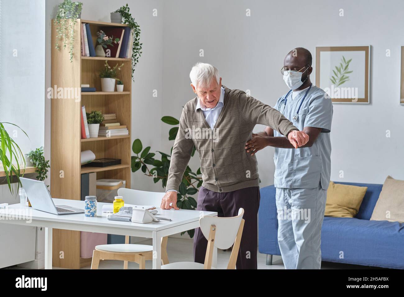 Medico maschile africano che esamina il paziente anziano durante la sua visita in ufficio medici Foto Stock