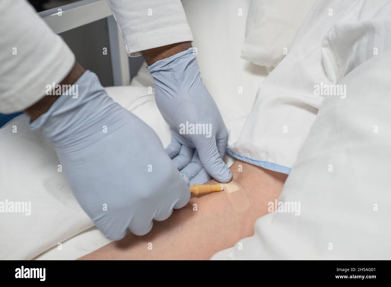 Primo piano del medico in guanti protettivi che mettono l'anestesia nel braccio di un paziente prima dell'intervento Foto Stock