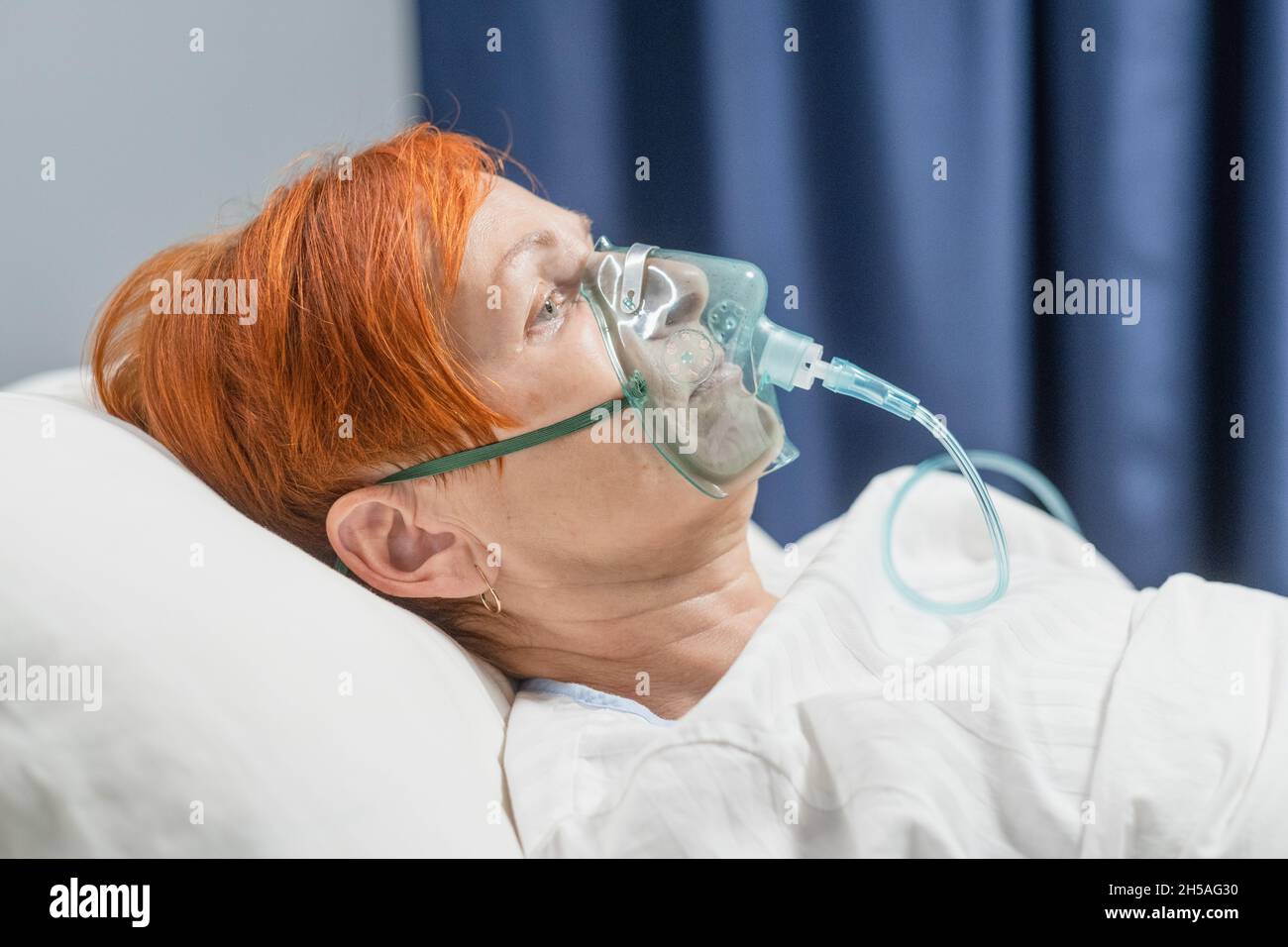 Primo piano di pazienti anziani che ricevono una maschera di ossigeno giacente su un letto dell'ospedale durante la pandemia in ospedale Foto Stock