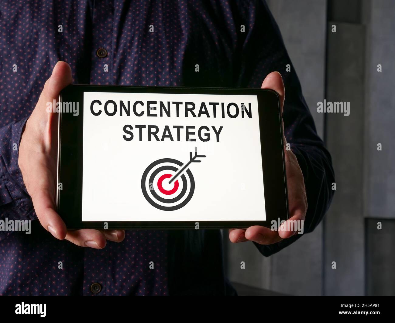Concetto di strategia di concentrazione. L'uomo mostra una tavoletta con iscrizione. Foto Stock