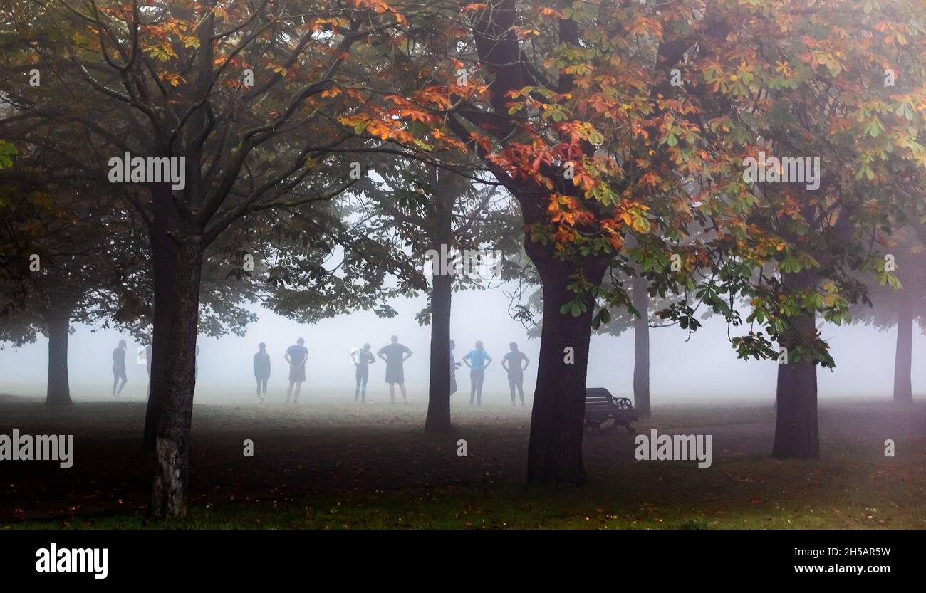 Misty mattina d'autunno a Greenwich Park con lezione di fitness presto per un allenamento, Londra Foto Stock