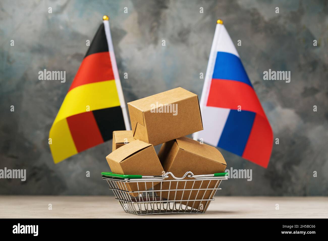 Scatole di cartone in un cesto di prodotti alimentari e due bandiere su sfondo astratto, il concetto di commercio tra Germania e Russia Foto Stock