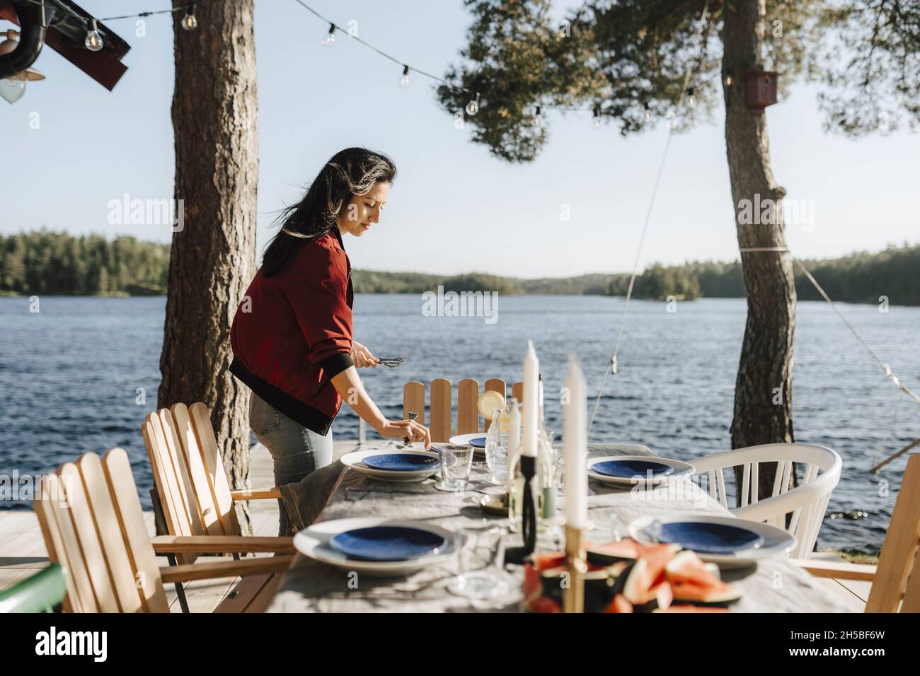 Giovane donna che fissa tavolo da lago in giorno di sole Foto Stock