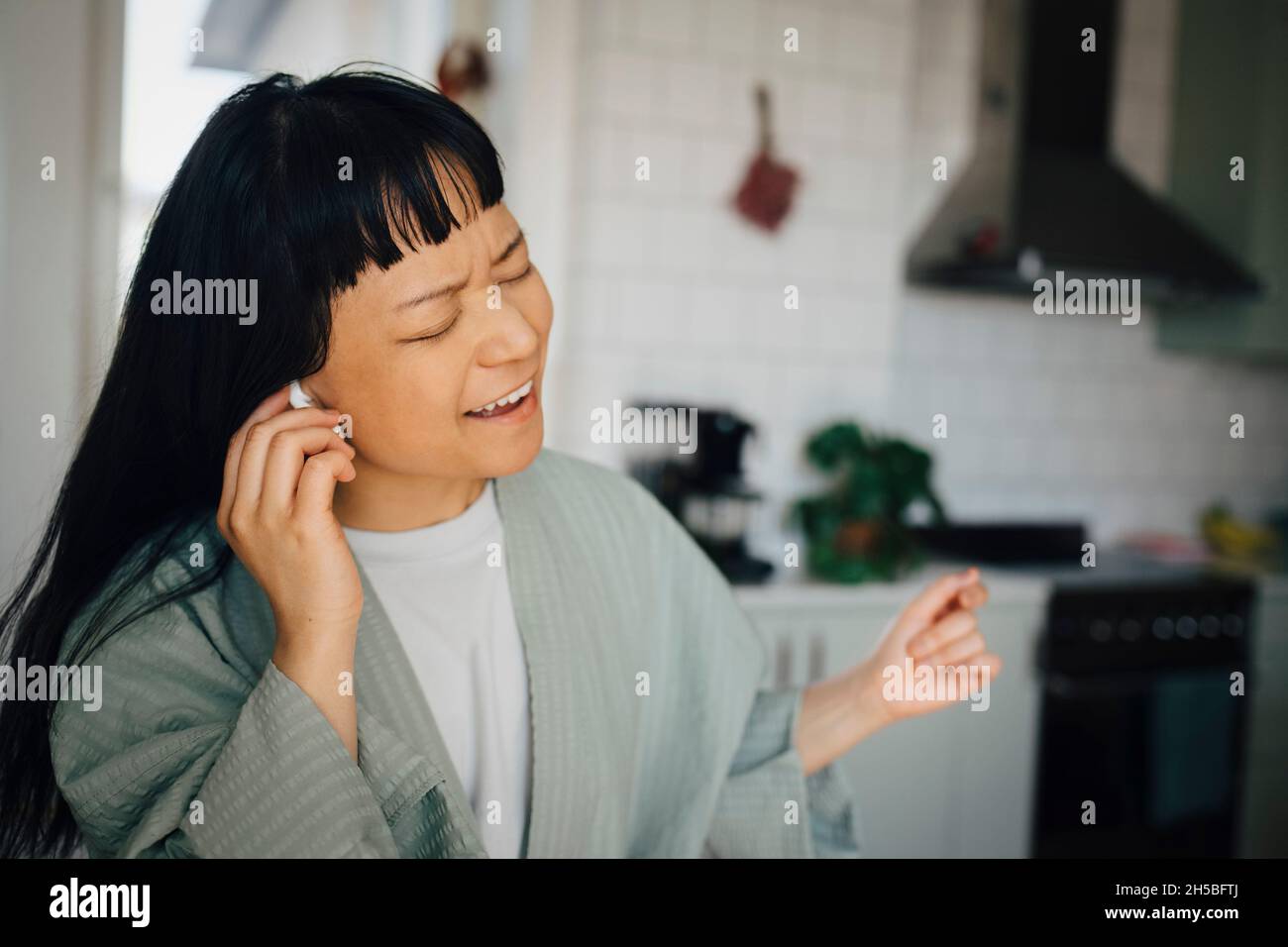 Ragazza allegra che canta mentre ascolta la musica a casa Foto Stock