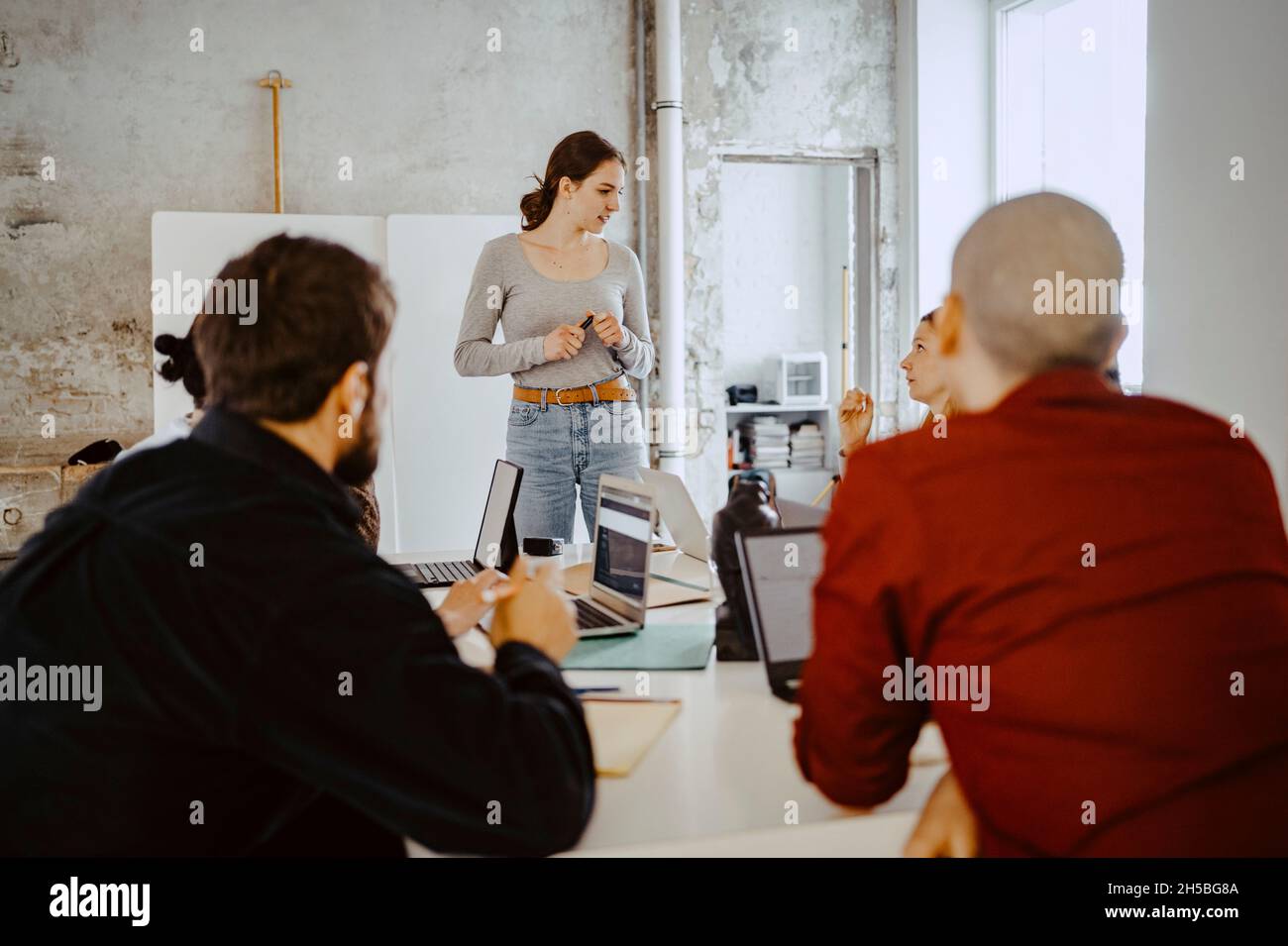 Imprenditrice femminile che discute con i colleghi in azienda startup Foto Stock