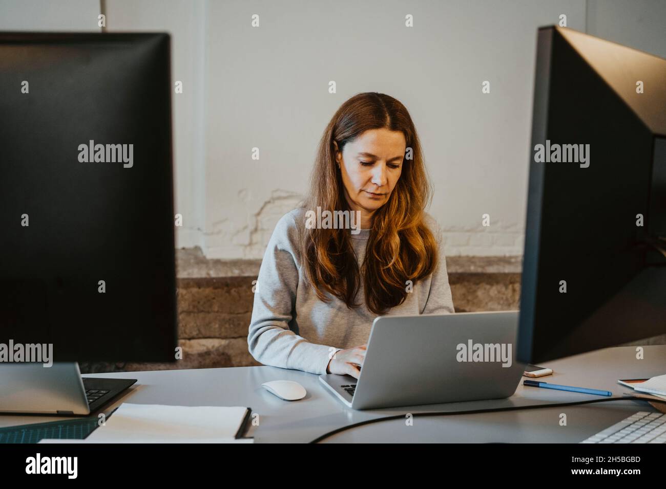 Programmatore femminile maturo che lavora su un laptop in ufficio Foto Stock