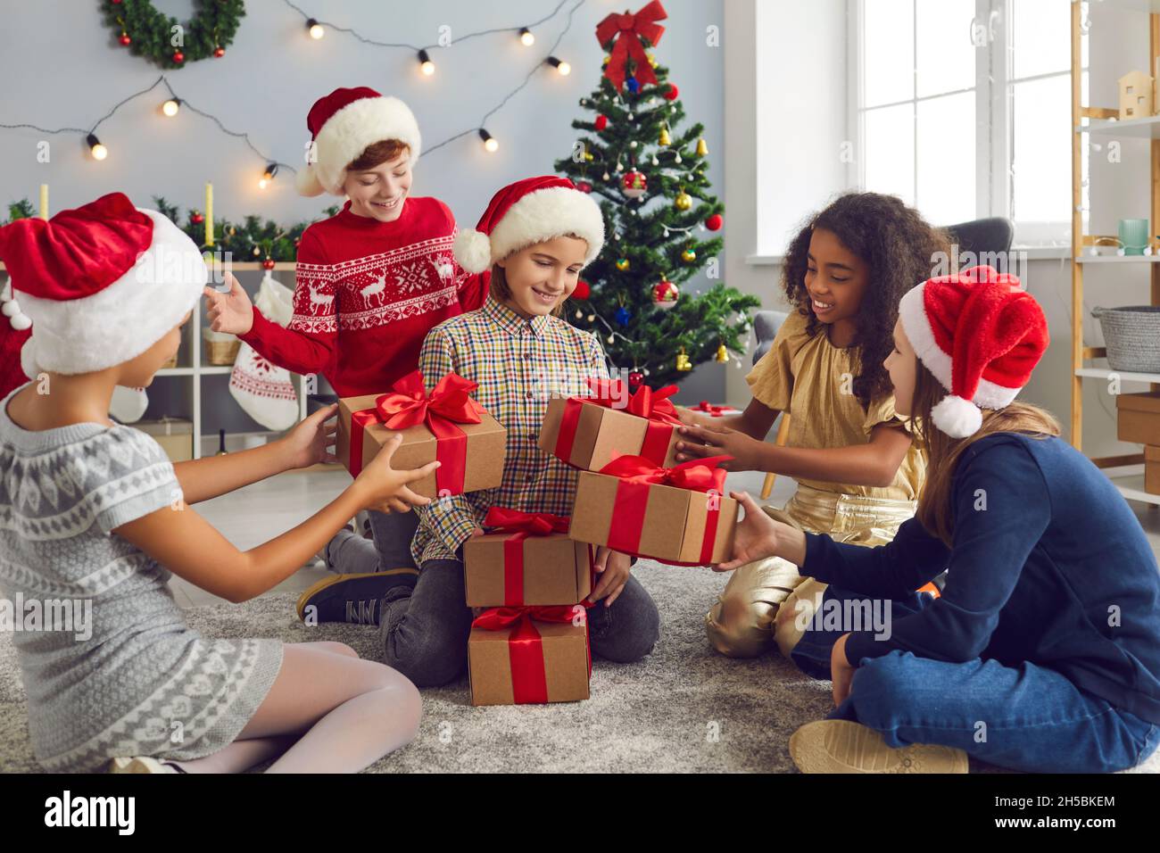 Ragazza felice che riceve i lotti dei regali di Natale dai suoi amici generosi o fratelli Foto Stock