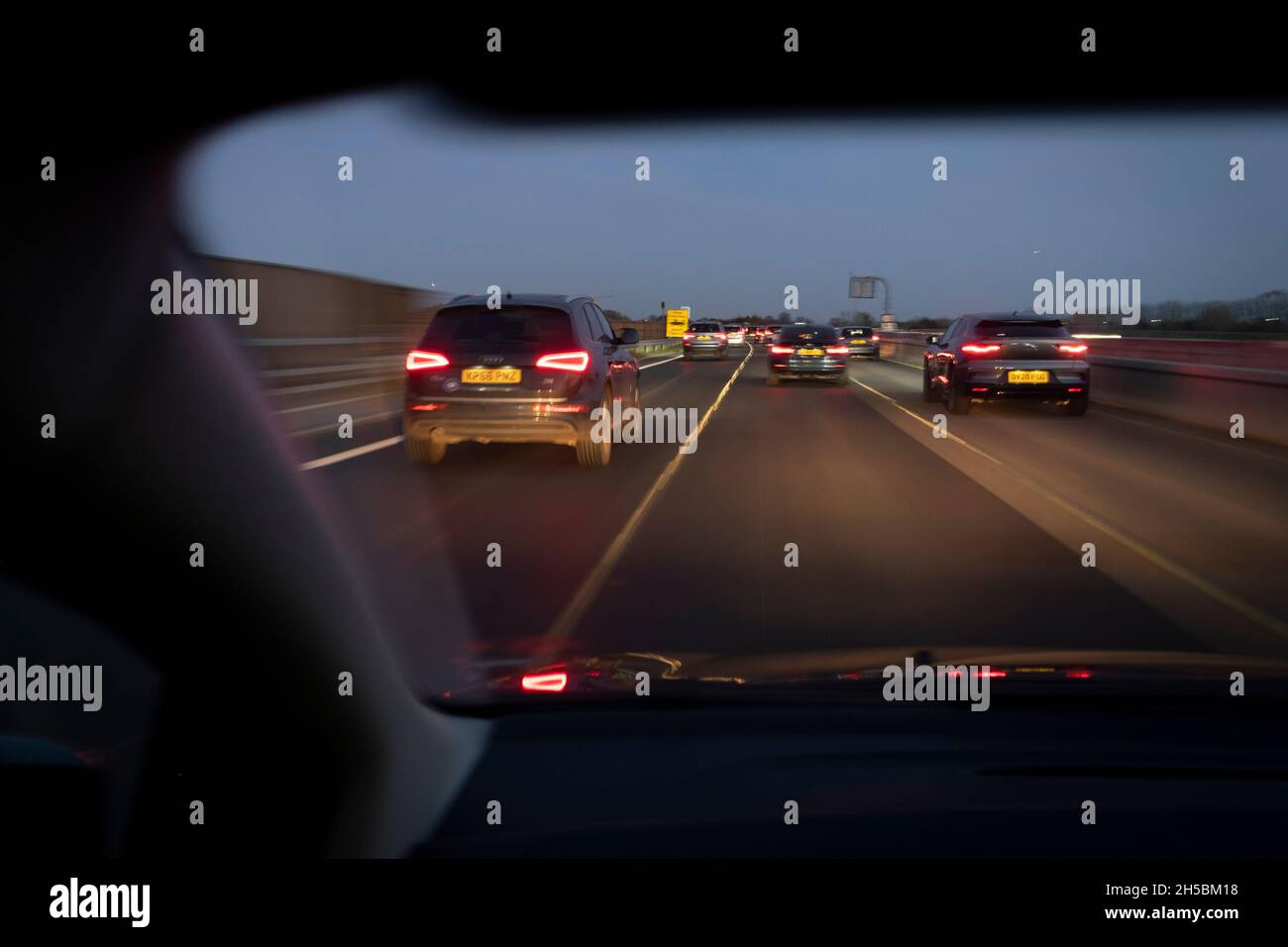 Visto dal sedile passeggero di un'auto, la luce invernale si affievolisce nell'oscurità attraverso il parabrezza il cui conducente utilizza Google Maps per navigare verso est verso Londra sull'autostrada M4, il 7 novembre 2021, a Londra, Inghilterra. Foto Stock