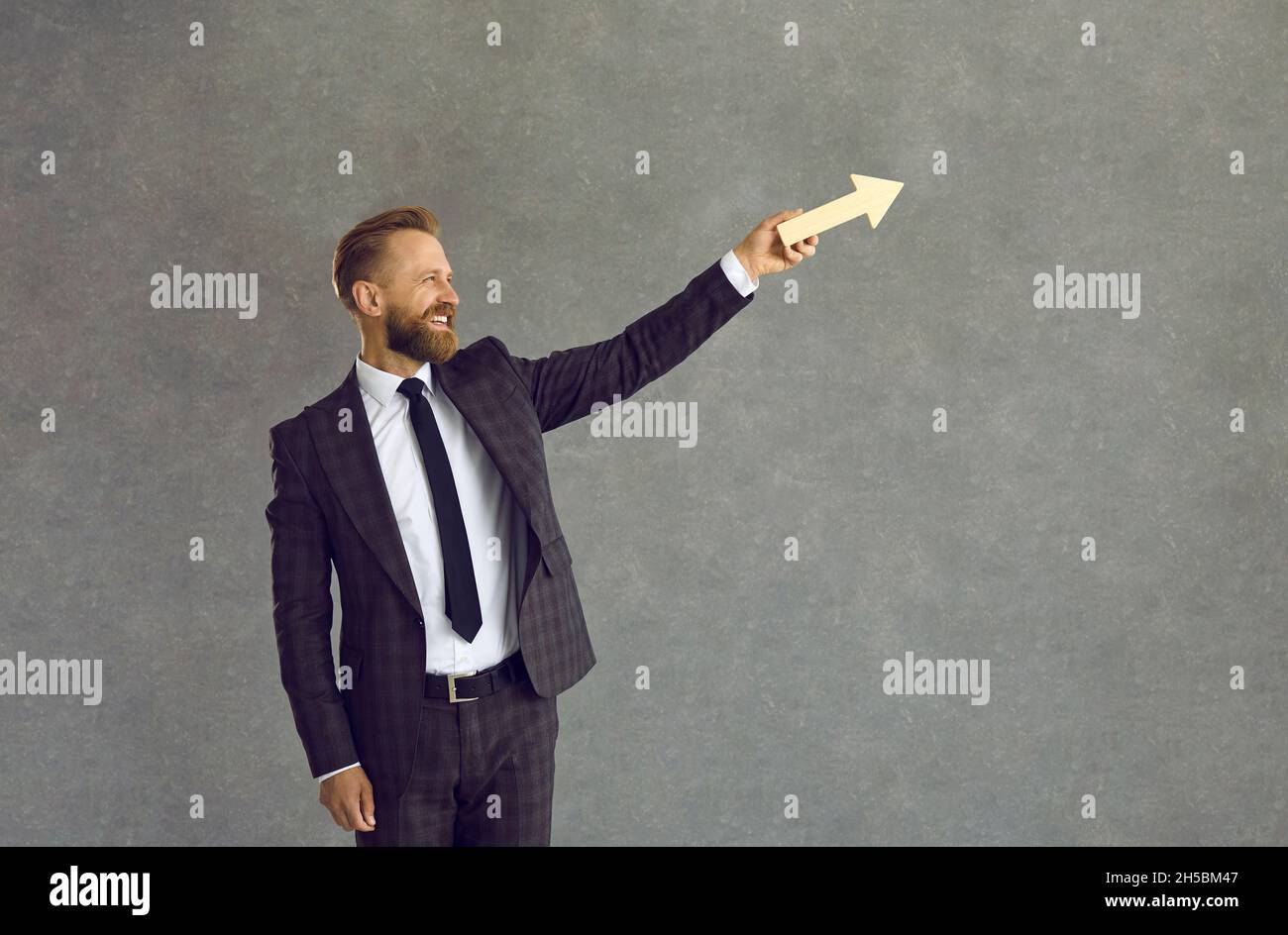 Un uomo d'affari felice che tiene freccia che va in su come simbolo di crescita di affari e di successo Foto Stock