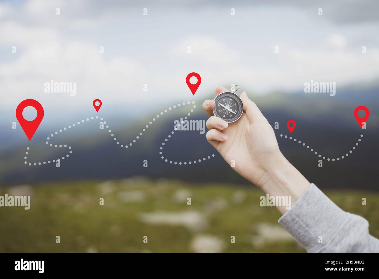 Percorso di progressione della montagna. La mano del viaggiatore tiene una bussola nelle montagne durante la vacanza. Intestazione orizzontale con posizione per il testo Foto Stock