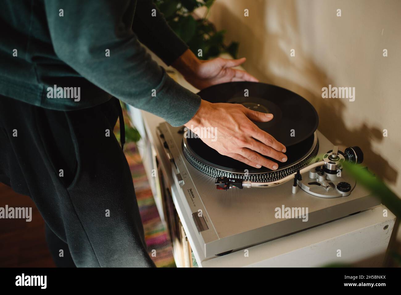 Giovane ippico misto corsa millennial rilassarsi e rilassarsi in appartamento ascoltando dischi in vinile. Suonare dischi vinilici, giovani mani che girano dischi Foto Stock
