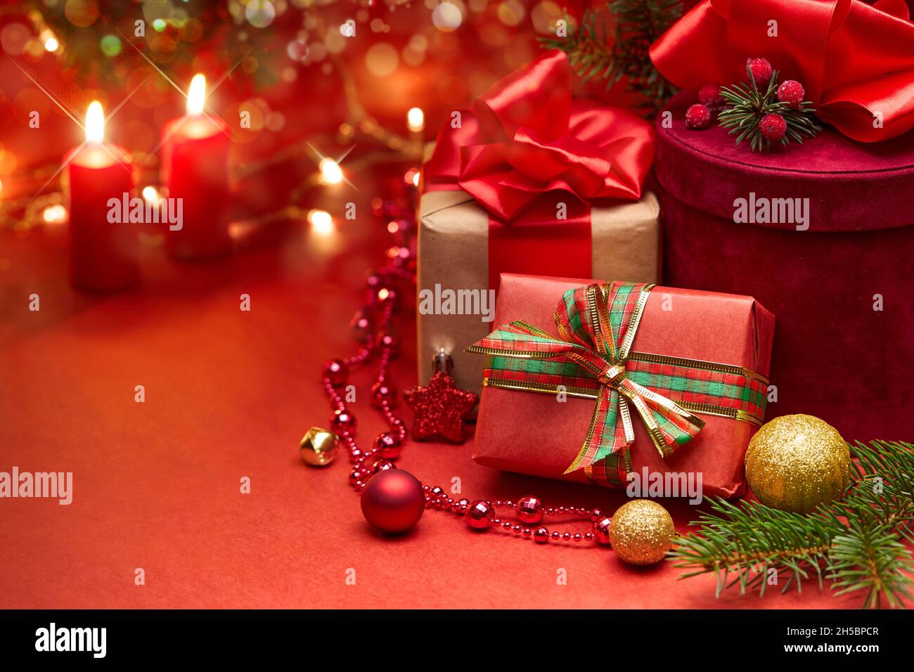 Scatole regalo di Natale e candele su sfondo rosso. Foto Stock