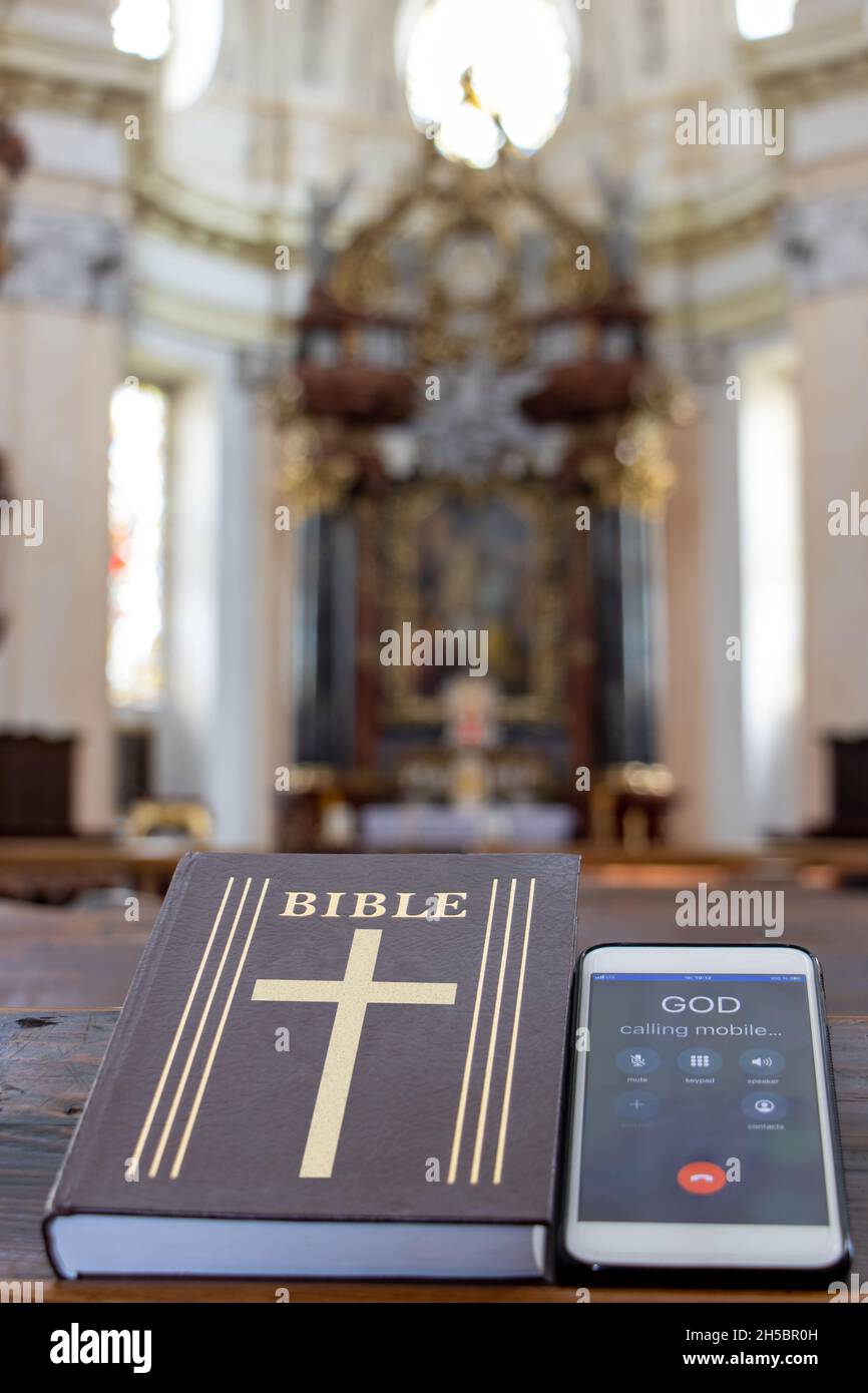 La Bibbia con telefono cellulare sul tavolo di una panchina di preghiera nella chiesa. Foto Stock