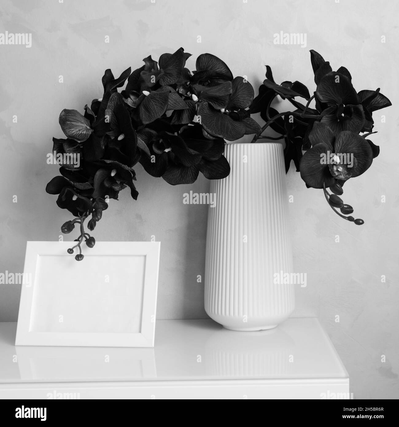 Orchid fiori in vaso e photoframe su armadio a parete Foto Stock