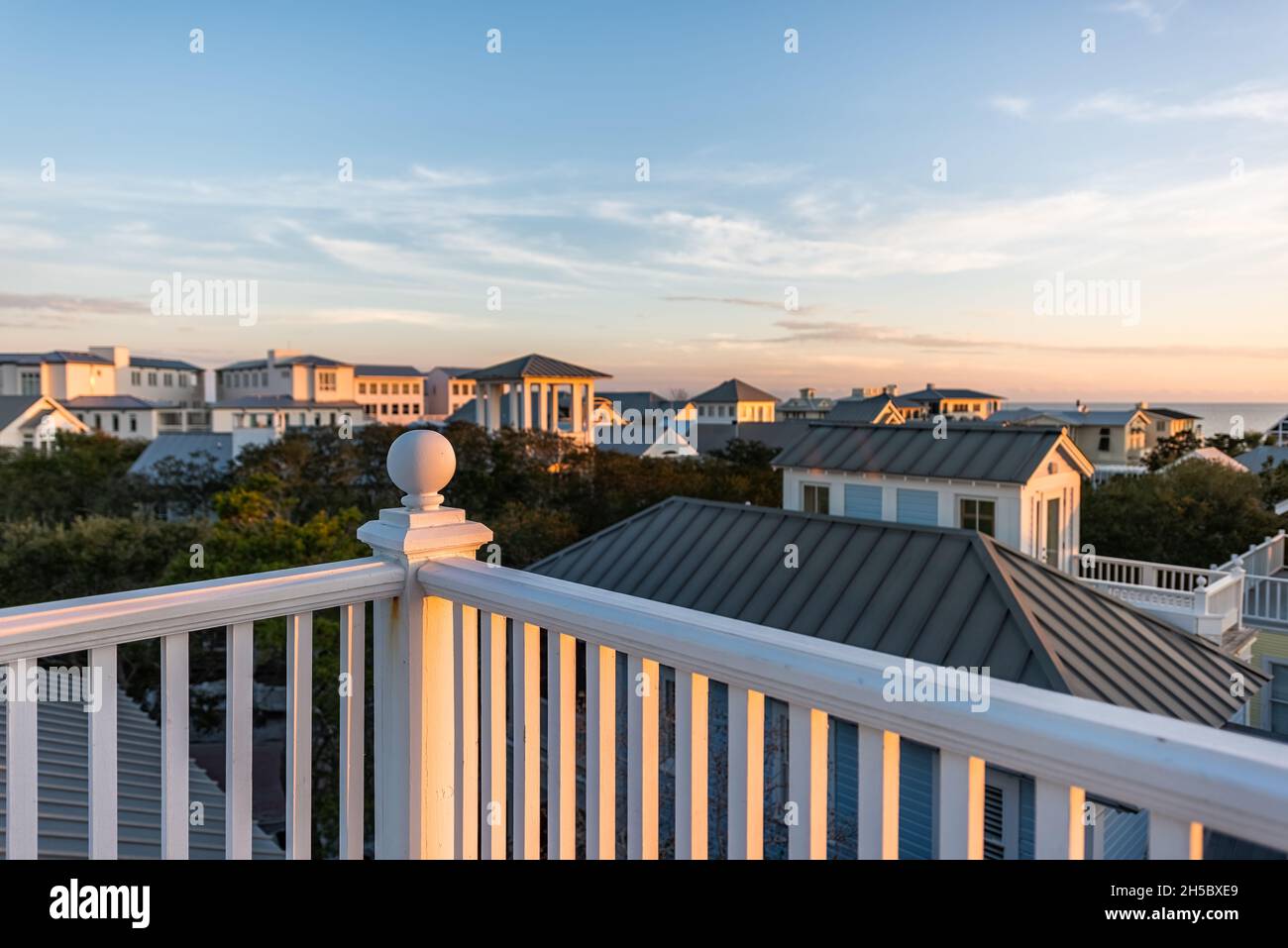 Tramonto a Seaside, Florida Golfo del Messico, vista dal tetto in legno terrazza edificio balcone con case paesaggio urbano e ringhiera bianca balaustra palla t Foto Stock