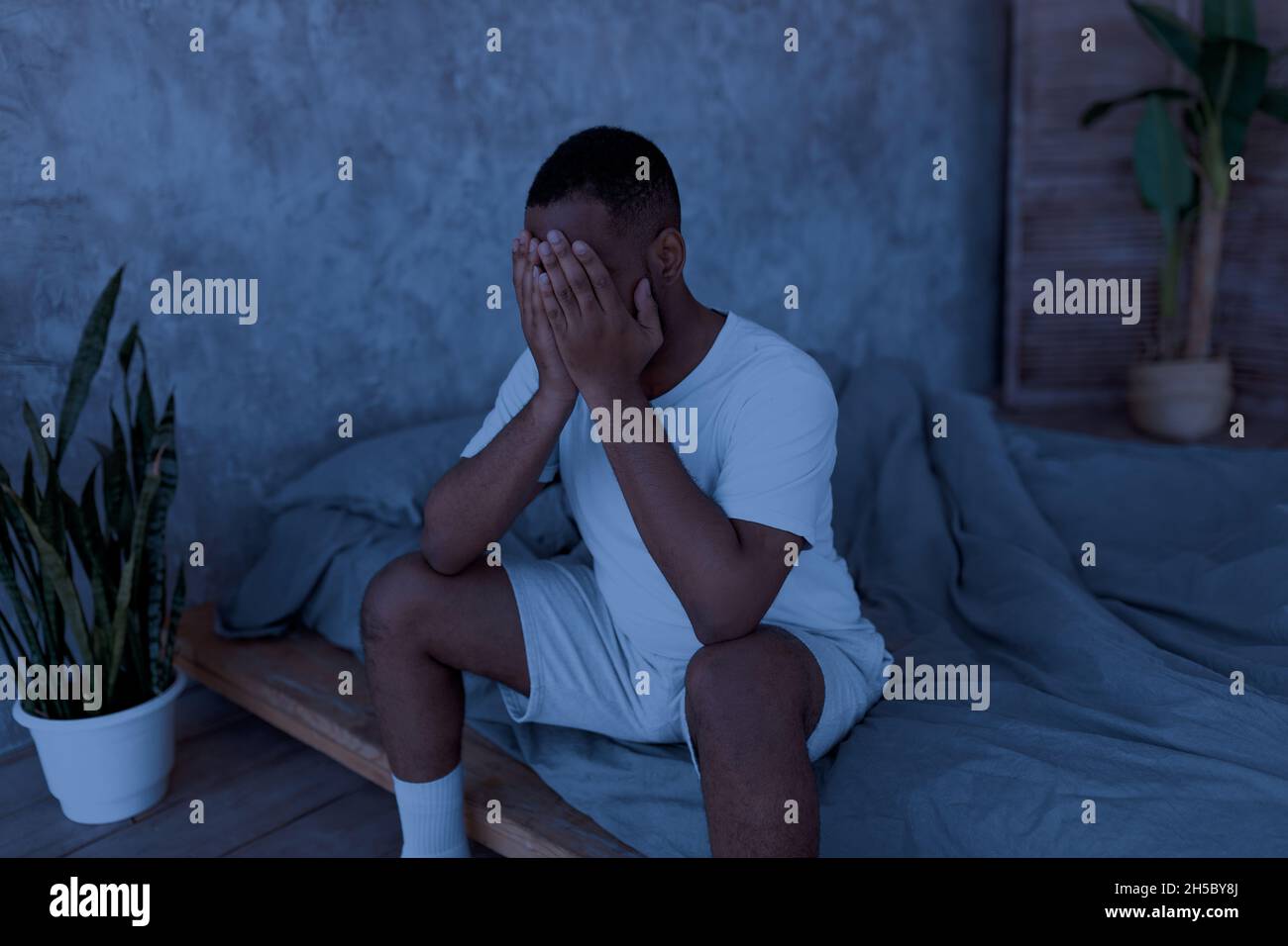 Uomo nero che soffre di insonnia seduta a letto Foto Stock